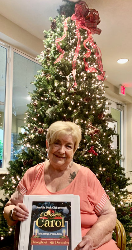 assisted living resident with Christmas tree and A Christmas Carol Book