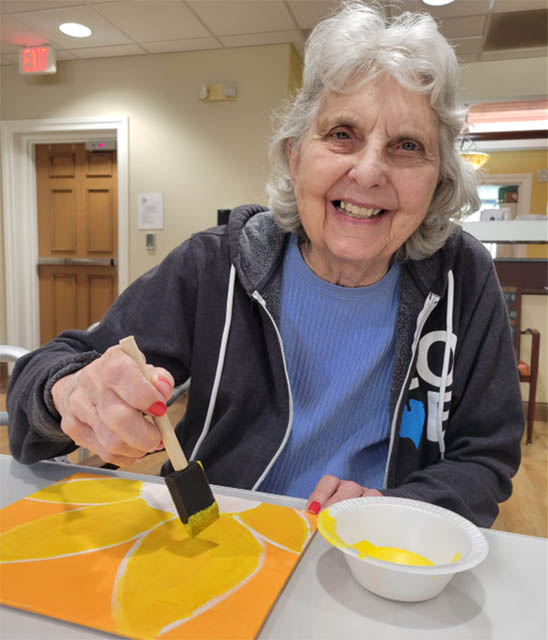 memory care resident smiling while painting