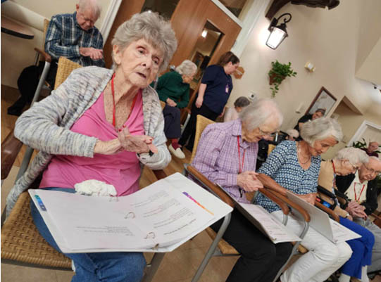 memory care residents follow the lyrics in her song book