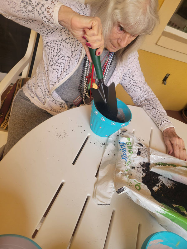 memory care resident painting flowerpot