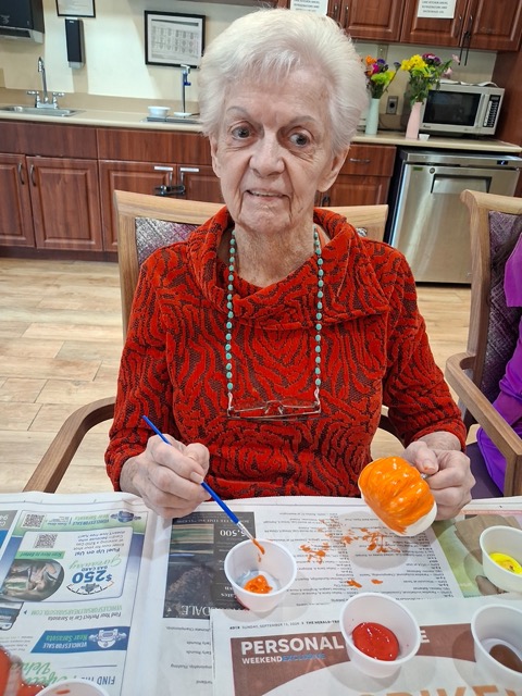 senior resident painting pumpkins